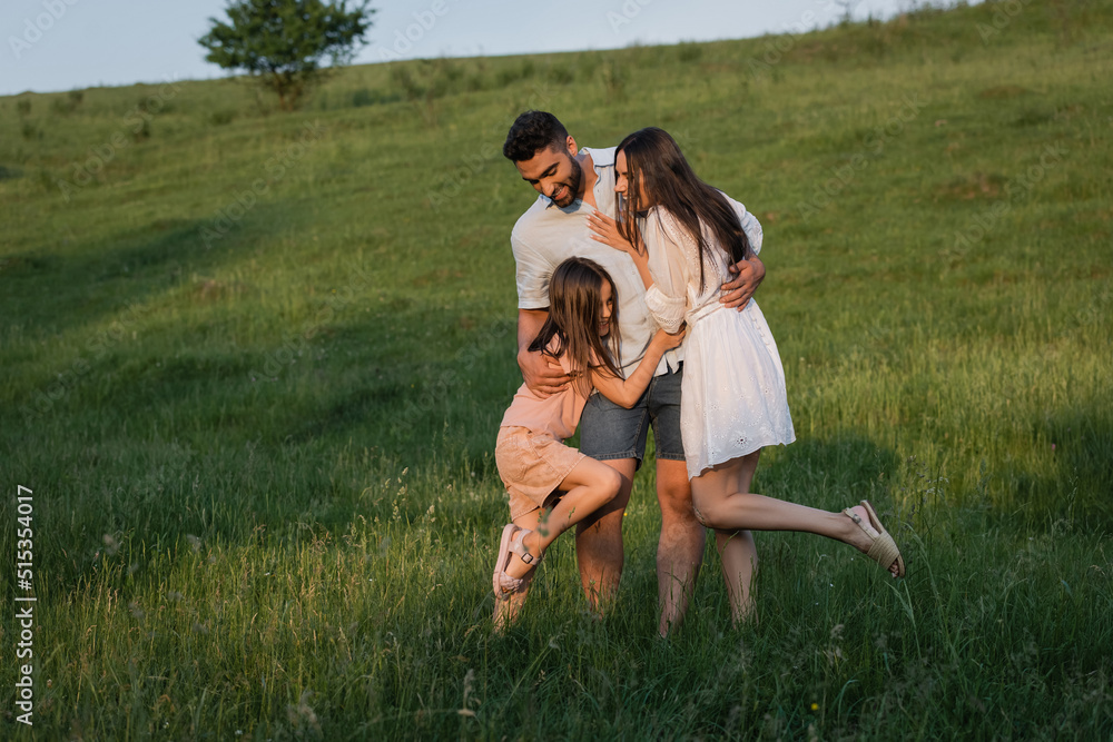 full length of happy family embracing in field on summer day. full length of happy family embracing in field on summer day.