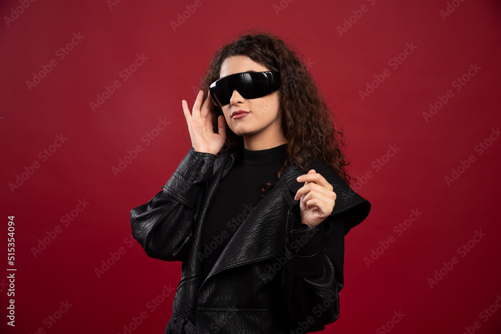 Curly young woman in black glasses on red background Curly young woman in black glasses on red background