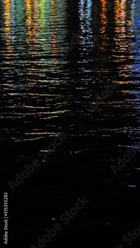 Colourful light reflection on water surface at night, verticall video photo