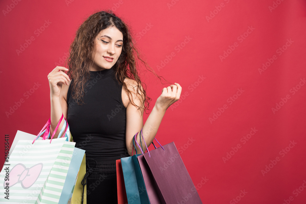 Woman showing her new buying clothes on red background Woman showing her new buying clothes on red background