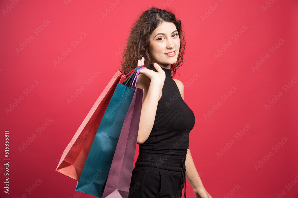Woman showing her new buying clothes on red background Woman showing her new buying clothes on red background
