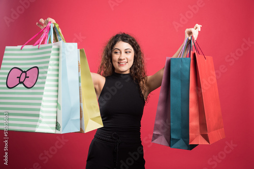 Happy woman with many of bags on red background
