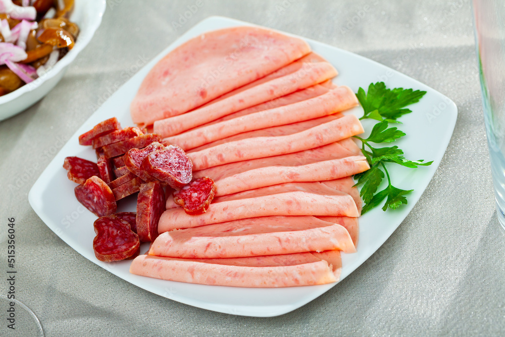 Appetizing cold cuts from Spanish ham, spicy dry-cured sausages and bacon on white plate