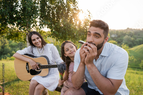 Quadro em tela man playing harmonica near daughter with bouquet and wife with acoustic guitar