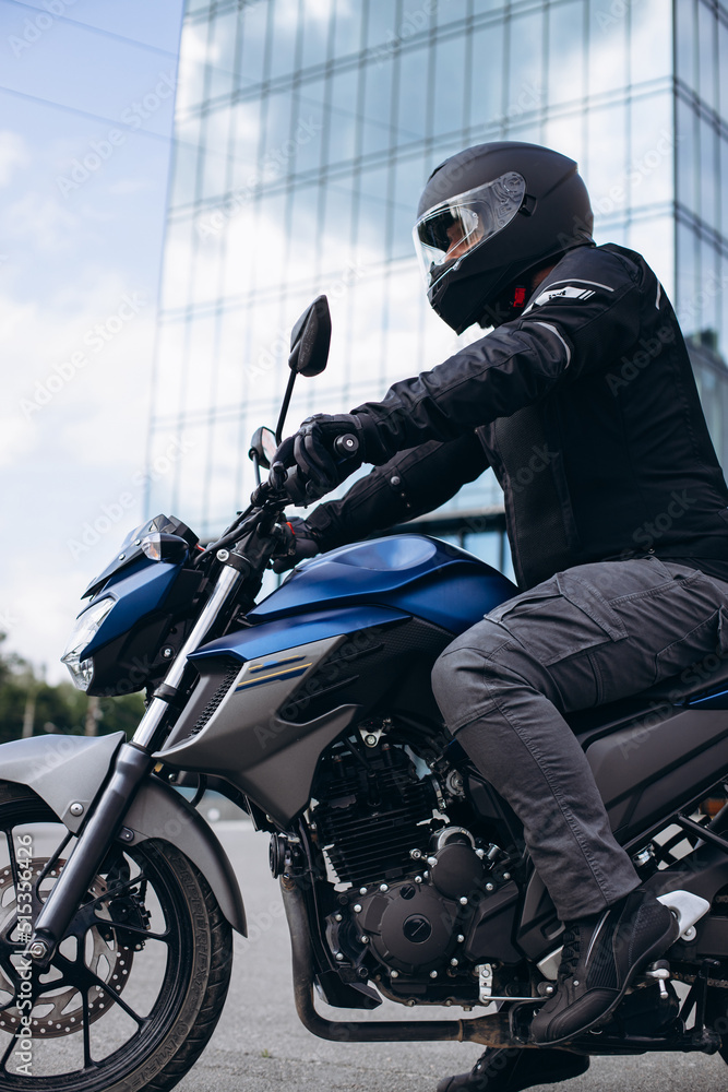 Naklejka premium Handsome motorcyclist on his moto riding in the city