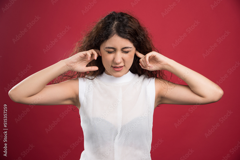Woman with closed ears on red background