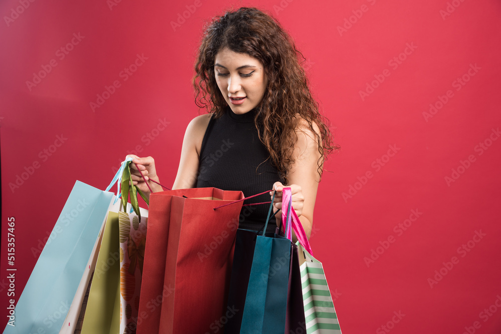 Woman looking on one of bag on red background
