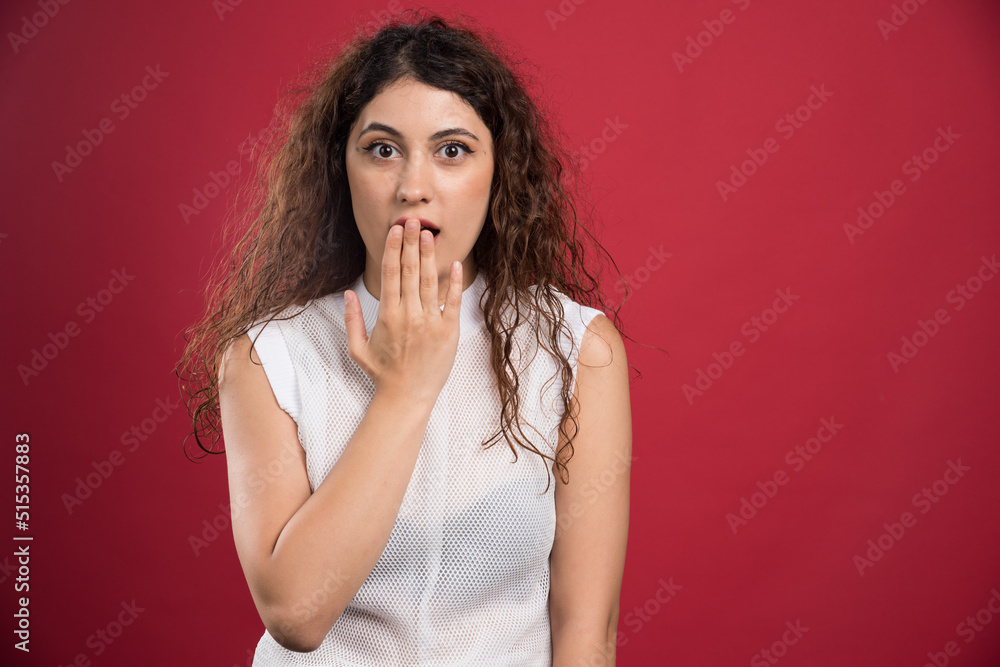 Young woman covering her mouth with close eyes on a red background Young woman covering her mouth with close eyes on a red background