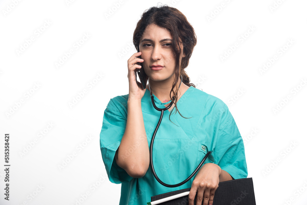 Young female doctor with clipboard and holding cell phone on white background Young female doctor with clipboard and holding cell phone on white background