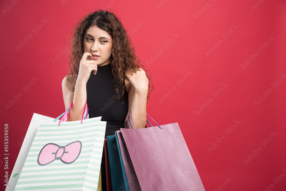 Woman showing her new buying clothes on red background Woman showing her new buying clothes on red background