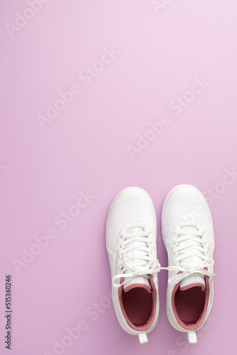 Sports concept. Top view vertical photo of white sneakers on isolated pastel lilac background with copyspace