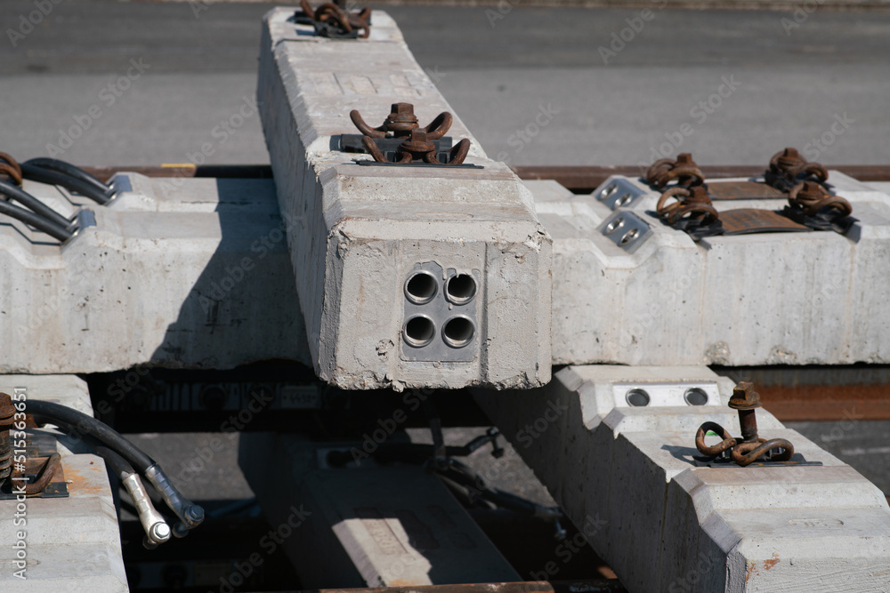 Stack of black and white concrete railway sleepers, for railway infrastructures, with parts with wiring elements, sensor systems and electrical cables. Stack of black and white concrete railway sleepers, for railway infrastructures, with parts with wiring elements, sensor systems and electrical cables.