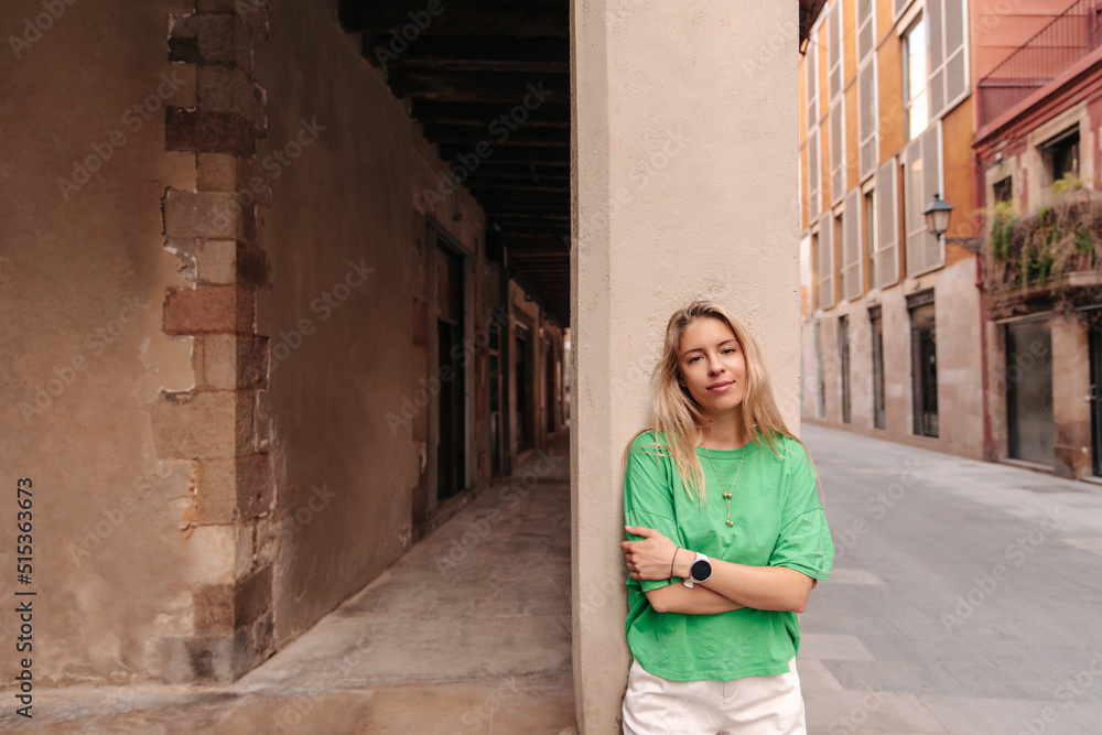 View of beautiful fair-haired woman wearing green t-shirt . European cute lady smiling and look at camera in the city View of beautiful fair-haired woman wearing green t-shirt . European cute lady smiling and look at camera in the city