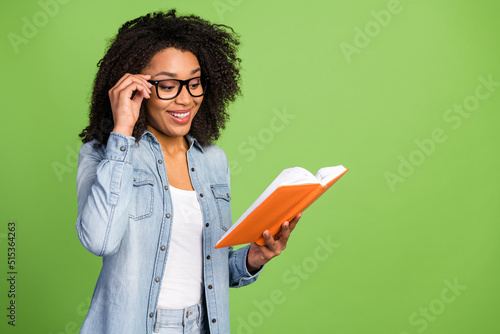 Profile side photo of young pretty woman read book hand touch eyeglasses isolated over green color background photo