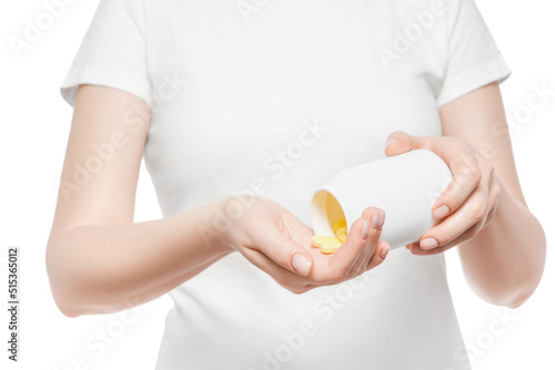 Cropped shot of a woman in white t-shirt pouring yellow pills in her hand from a white plastic bottle. Isolated.