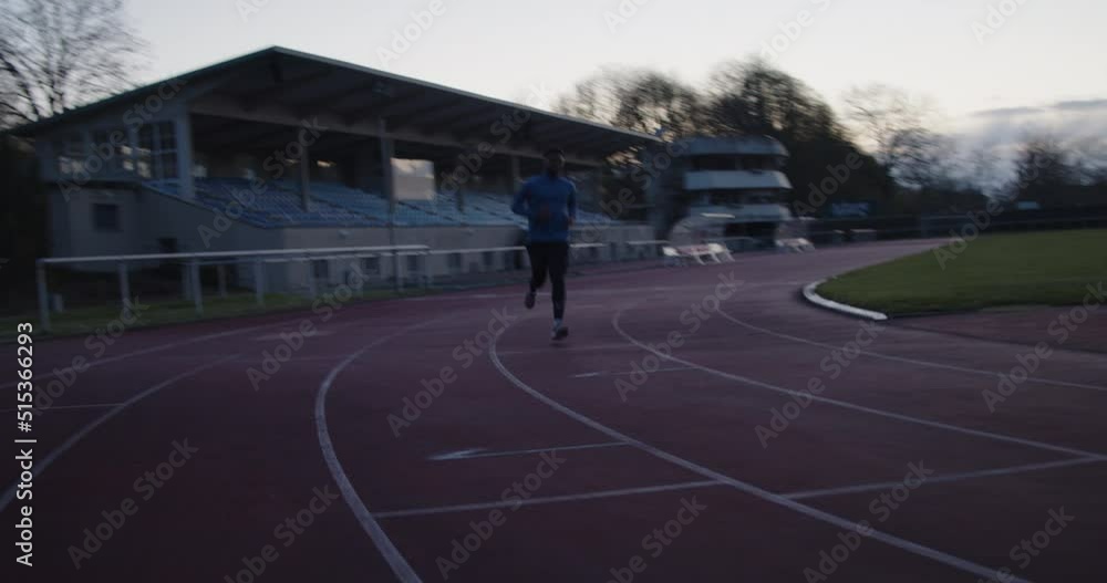 Young black runner doing his workout on the evening on empty running track with sunset in background. bmpcc 6k pro Young black runner doing his workout on the evening on empty running track with sunset in background. bmpcc 6k pro