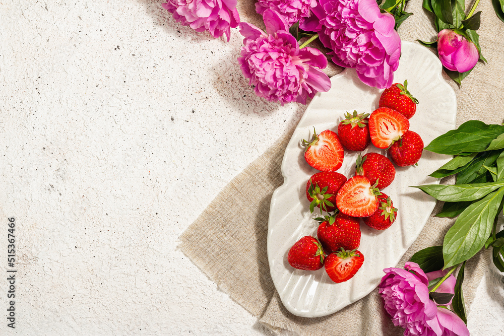 Sweet ripe strawberries and fragrant peonies bouquet. Summer plaster background, seasonal design