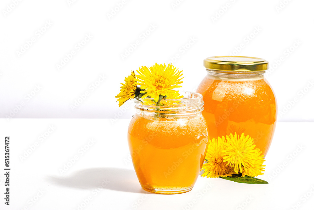 Dandelion jam or honey in the glass jar with fresh dandelion flowers isolated on white background Dandelion jam or honey in the glass jar with fresh dandelion flowers isolated on white background