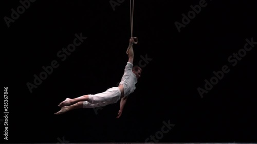 Muscular circus artist perform on the aerial straps on black background. Movement, strength concept photo