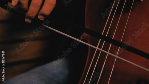 Closeup of man's hand playing cello. Baroc cello played holding the bow. Detail of vibrating cords. photo