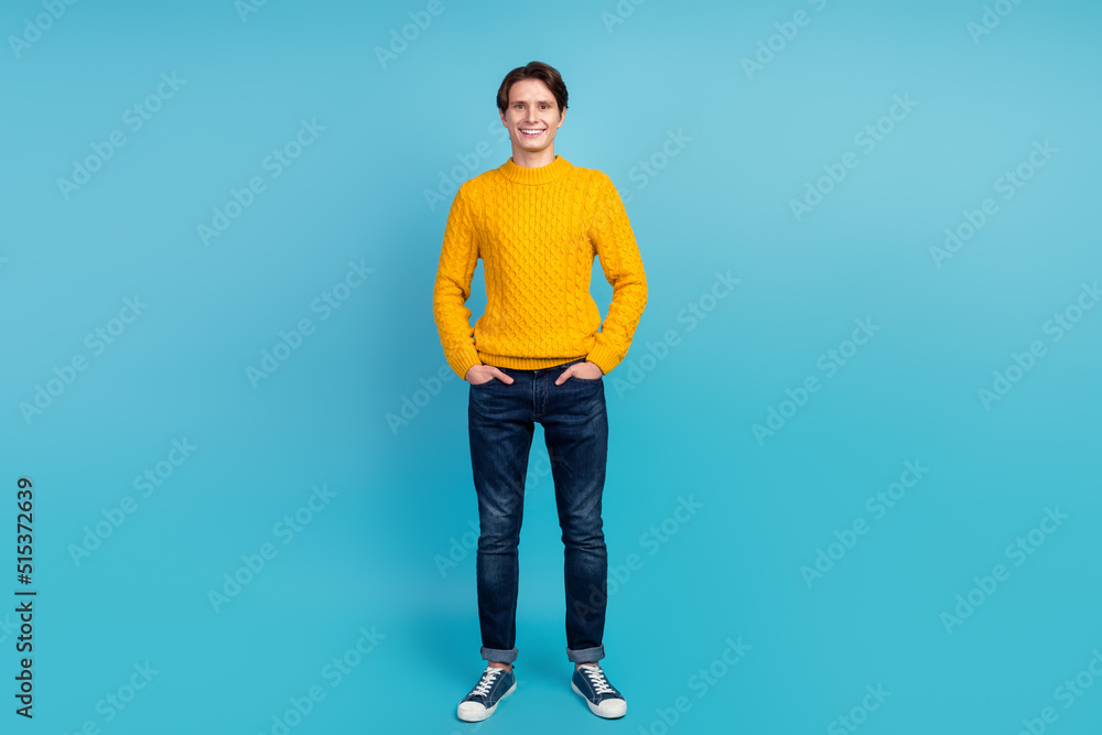 Full length photo of optimistic modern youngster standing isolated blue wall stusio shot hands pockets Full length photo of optimistic modern youngster standing isolated blue wall stusio shot hands pockets