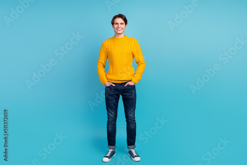Full length photo of optimistic modern youngster standing isolated blue wall stusio shot hands pockets © Tetiana