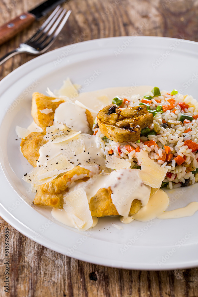 Chicken breast with cheese sauce, parmesan and rice with vegetables. Chicken breast with cheese sauce, parmesan and rice with vegetables.