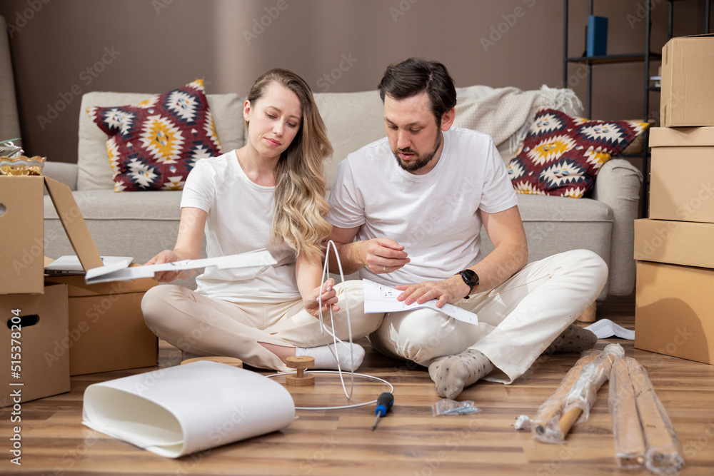 Happy couple moving into their new home. Assembling furniture. The couple assembles a lamp according to the instructions. Happy couple moving into their new home. Assembling furniture. The couple assembles a lamp according to the instructions.