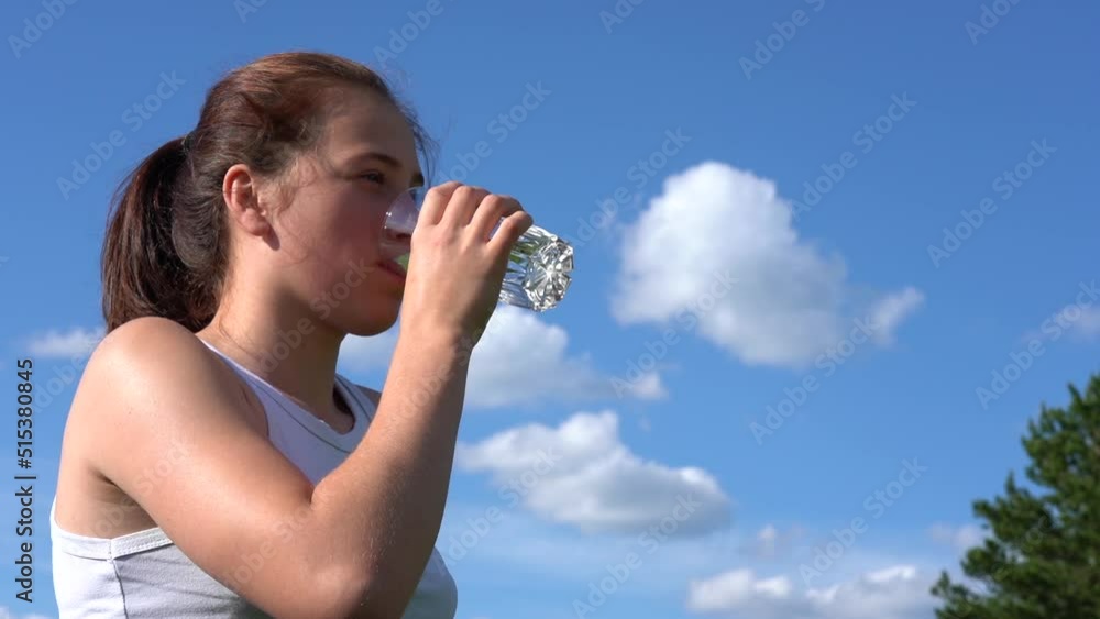 Athletic young woman drinking water from a glass in the park on a sunny day Athletic young woman drinking water from a glass in the park on a sunny day