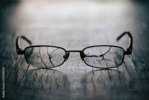 On an old, wooden background, men's glasses with cracked glasses, studio photography, close-up.
