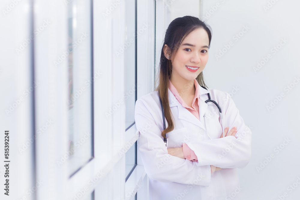 Professional Asian female doctor with black long hair wears a white lab coat and stethoscope. She stands and cross arms in office at hospital. Professional Asian female doctor with black long hair wears a white lab coat and stethoscope. She stands and cross arms in office at hospital.