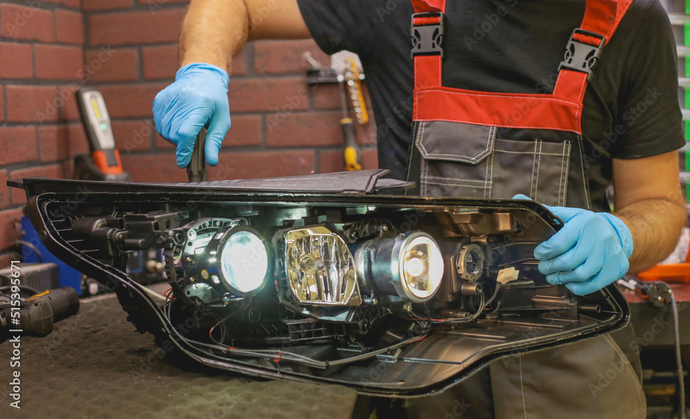Car headlight in repair closeup. The car mechanic installs the lens in