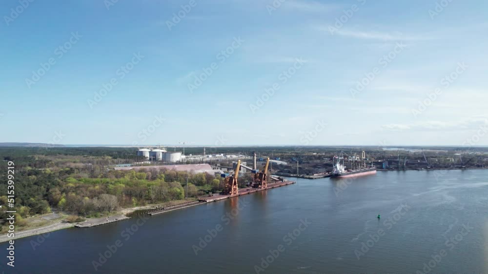 Aerial view of a cargo ship being unloaded by huge cranes in a port. Transport of loose mineral resources. Aerial view of a cargo ship being unloaded by huge cranes in a port. Transport of loose mineral resources.
