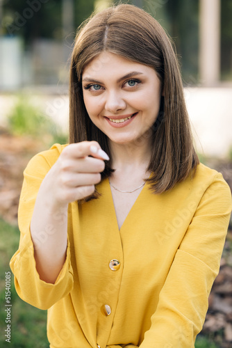 Hey you, come here. European ukraininan girl pointing index finger at camera inviting with hand gesture. Young ethnic happy woman calling to showing something and speaking body language photo