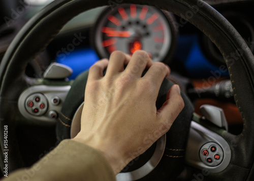 Close-up of the driver's hand on the steering wheel of the car. A man's hand on the steering wheel of a modern car close-up, selective focus.