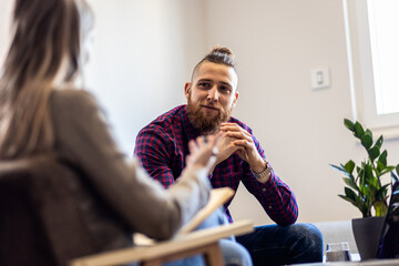 Young man talking to female psychologist during session.
