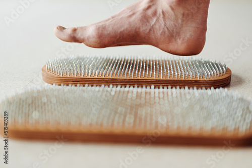 Woman try standing on Wooden Sadhu board with nails, yoga desk for regular practice, relieves nervous stress, tiredness, emotional overexcitation