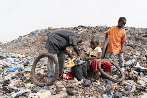 Three homeless street boys in a landfill with their daily loot of garbage to recycle and sell; condition of slum children in Africa