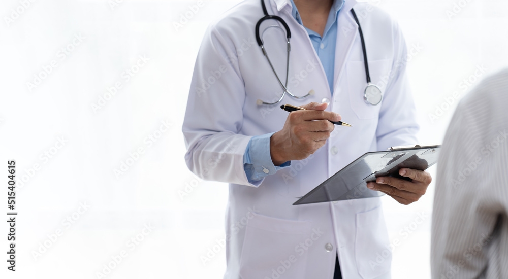 Doctor and patient sitting and talking at medical examination at hospital office, close-up. Therapist filling up medication history records. Medicine and healthcare concept. Doctor and patient sitting and talking at medical examination at hospital office, close-up. Therapist filling up medication history records. Medicine and healthcare concept.