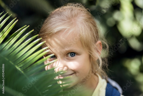 Wallpaper Mural Children and Nature. Travel and rest with Kids. Child Portarait on Nature Background. Girl behind palm branch, tropical green leaf.  Torontodigital.ca