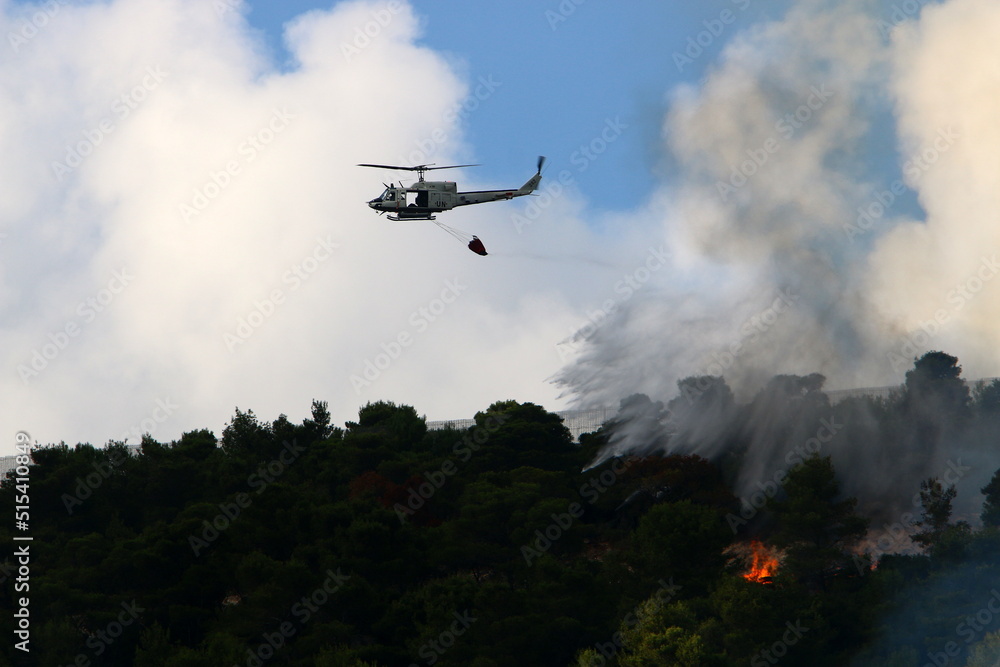 Fototapeta premium A UN helicopter puts out a fire in a forest on the Israel-Lebanon border.