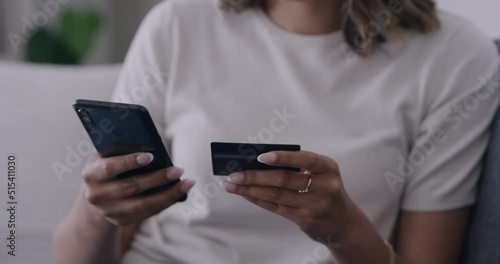 Womans hand using a phone and credit card and buying products electronically. Unknown female shopping online and paying bills digitally. Person doing internet banking conveniently from home