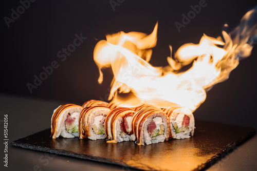 Preparing of sushi rolls with a fire on black background