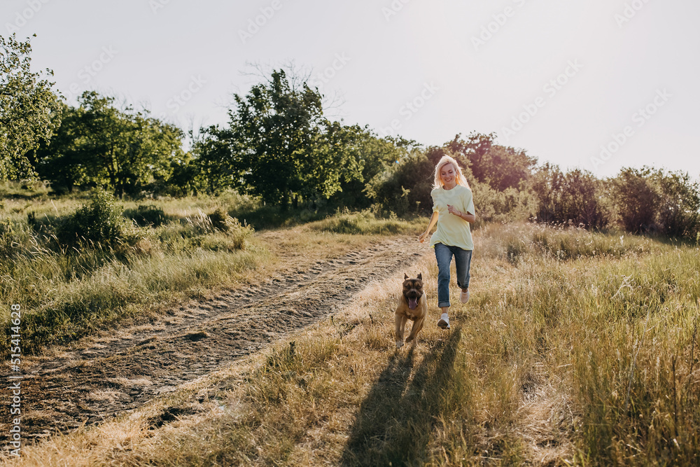 Woman running with her dog in nature on summer evening. 