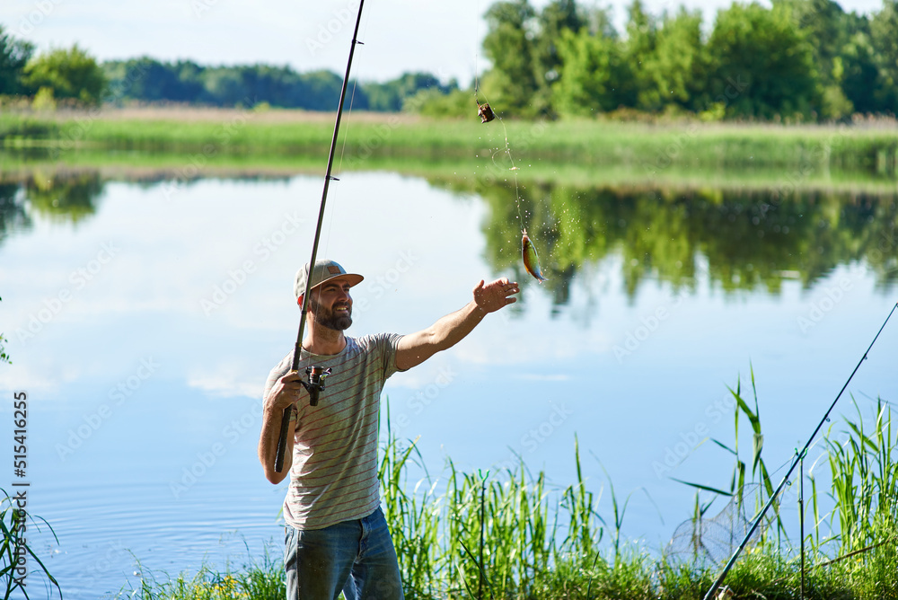Fisherman catching a fish (roach) by spinning. Standing in the side of the river. Lifestyle for adult. Fisherman catching a fish (roach) by spinning. Standing in the side of the river. Lifestyle for adult.
