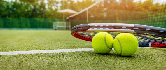 tennis racket and balls on synthetic grass outdoor court. banner with copy space