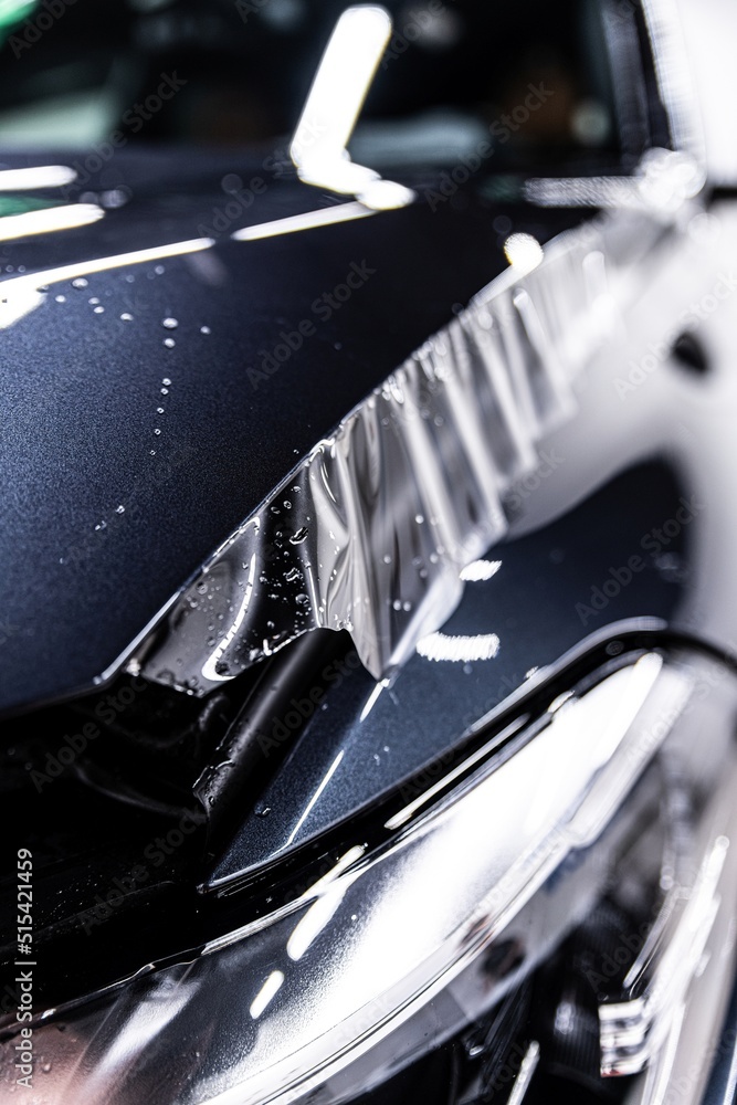 Hood of a modern car during the application of a tranparent protective film in a car detailing studio