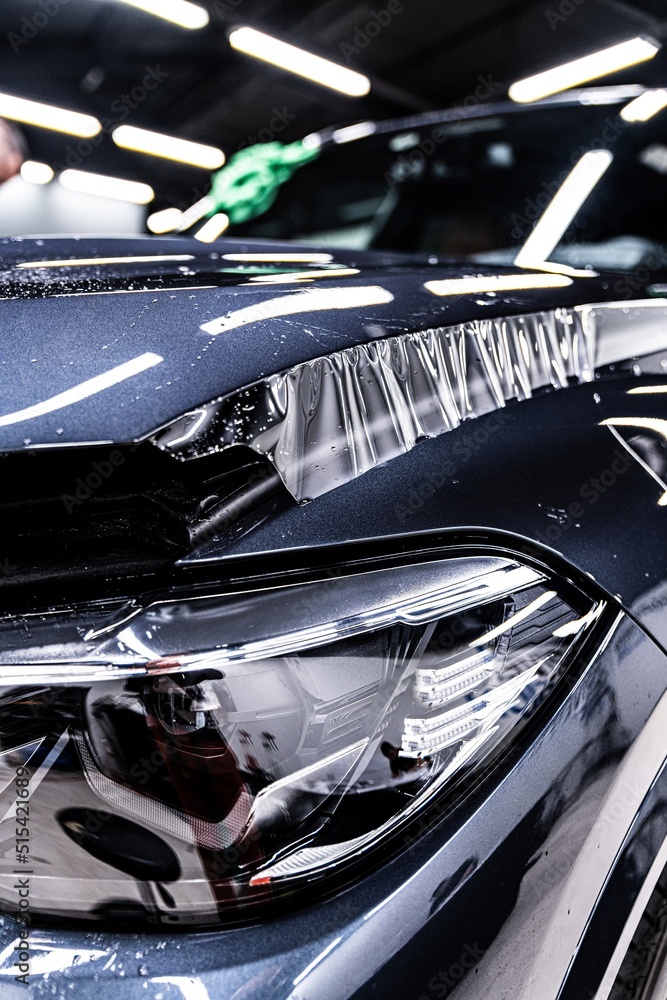 Hood of a modern car during the application of a tranparent protective film in a car detailing studio