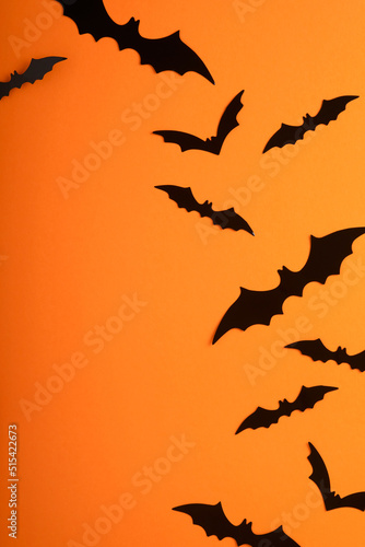 Orange Halloween background. Flock of black bats for Halloween. Black paper bat silhouettes on orange background. Halloween concept, Copy space, top view, overhead.