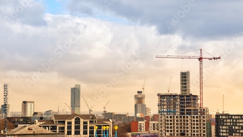 City view with modern buildings and construction work with large cranes. Manchester skyline at sunset. 